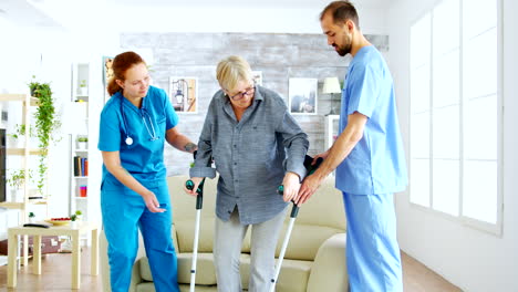Senior-woman-with-crutches-getting-help-for-female-nurse