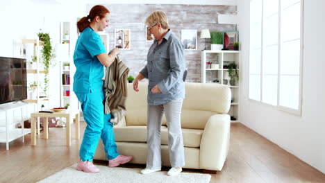 Female-nurse-helping-senior-woman-getting-dressed