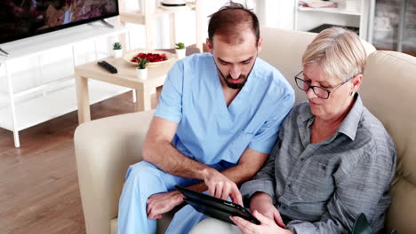 Male-nurse-teaching-elderly-old-woman-how-to-use-her-tablet-PC