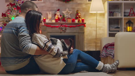 Happy-married-couple-sitting-on-the-carpet-in-front-of-fireplace