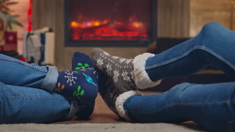 Couple-wearing-woolen-socks-in-front-of-fireplace