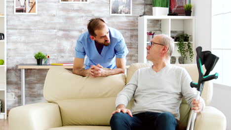 Elderly-man-having-a-conversation-with-a-male-nurse-in-cozy-nursing-home