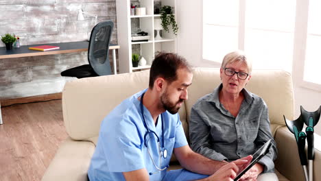 Male-nurse-holding-tablet-computer-in-retirement-home