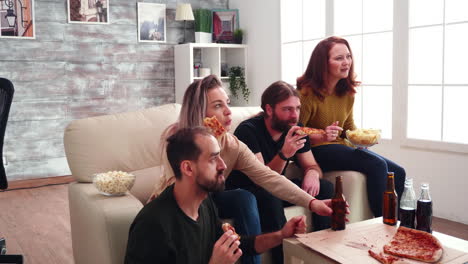 Group-of-close-friends-with-mouth-full-of-pizza-celebrating-victory