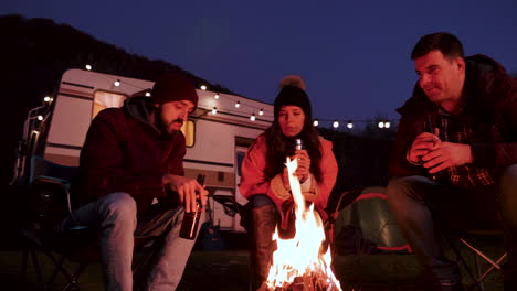 Caucasian-bearded-man-telling-a-story-to-his-friends-around-camping-fire