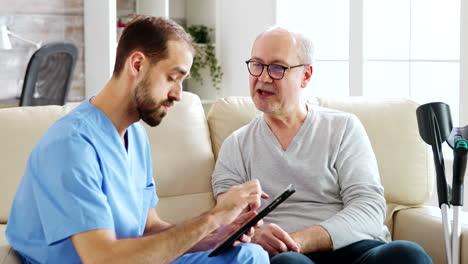 Caucasian-male-nurse-talking-with-a-nursing-home-patient-about-his-health