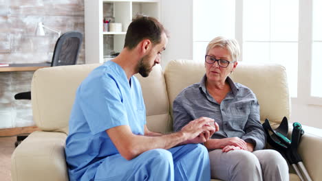 Male-doctor-assistant-sitting-on-the-couch-with-senior-woman