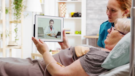 Alte-Behinderte-Frau-Liegt-Im-Krankenhausbett-Und-Führt-Einen-Online-Videoanruf-Mit-Einem-Arzt
