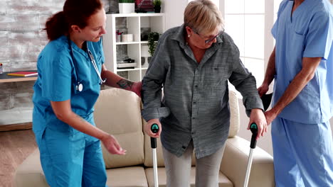 Elderly-woman-with-crutches-being-helped-by-nurse-team