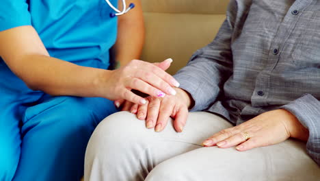 Close-up-of-female-nurse-holding-senior-woman-hand