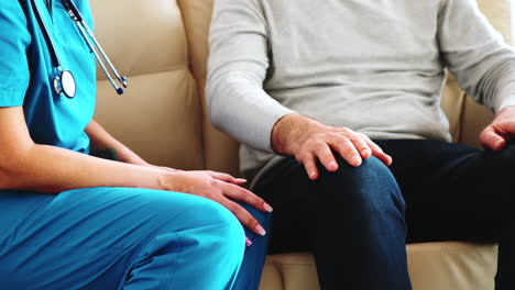 Close-up-shot-of-female-nurse-taking-an-old-man-hand-while-they-are-sitting-on-the-couch
