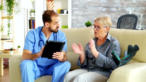 Bearded-doctor-holding-tablet-computer-in-nursing-home