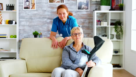 Pretty-nurse-in-nursing-home-and-old-woman-sitting-on-couch