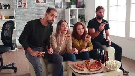 Group-of-friends-sitting-on-couch-eating-pizza