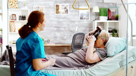 Female-nurse-in-retirment-home-giving-an-old-disabled-lady-a-VR-headset