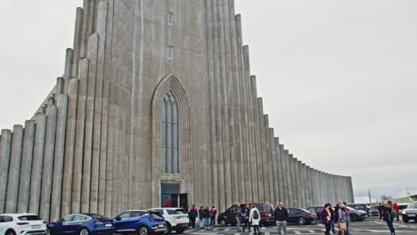 Tilt-up-from-busy-square-to-the-tall-Hallgrímskirkja-church-tower-in-Reykjavik,-Iceland
