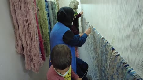 Middle-east-woman-weaving-knots-to-make-Persian-rug-carpet-colorful-handmade-craft-handicraft-at-home-with-natural-wool-material-nature-color-beautiful-pattern-economy-financial-life-traditional-skill