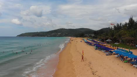 Zipline-aerial-drone-shot-of-Karon-beach,-a-popular-public-beach-among-local-and-foreign-tourists,-located-on-the-island-of-Phuket-in-Southern-Thailand