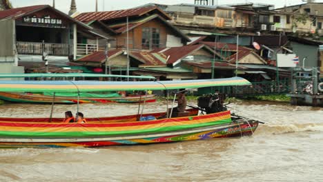 Tourist-couple-sailing-on-long-tail-boat-through-dirty-Chao-Phraya-river-in-Bangkok