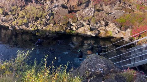 Tourists-snorkeling-in-cold-waters-of-Silfra-tectonic-fault,-Iceland