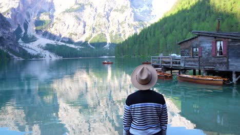 Man-with-a-hat-turns-back-and-smiles-in-Lago-di-Braies-in-Dolomites,-Italy