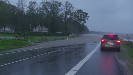 Vehicle-halts-before-flooded-road-in-Kollund,-Denmark,-by-Flensburg-Fjord