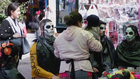 Revelers-get-skull-face-paint-for-Day-of-the-Dead-celebration,-Mexico