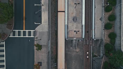 Aerial-top-down-shot-of-train-riding-on-rail-in-city-of-Atlanta-with-cars-in-road-during-cloudy-day
