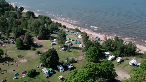 drone-view-of-people-camping-near-Baltic-sea-shoreline-with-tents-and-camper-vans