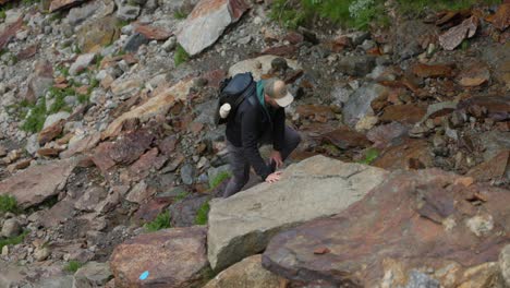 Male-Hiker-Carefully-Climbing-Over-Rocks-In-In-Valmalenco-Region-In-Italy