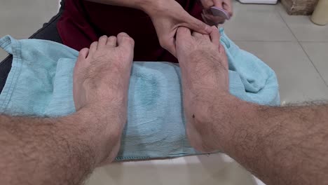 Man-getting-a-pedicure-by-person-with-a-file-in-clinic