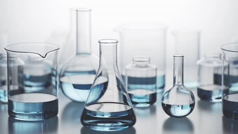 Versatile-laboratory-glassware-with-blue-liquid-inside-on-a-light-background.-Many-different-kinds-of-chemistry-containers-stacked-in-an-endless,-seamless-looping-pattern.-Camera-moving-sideways.