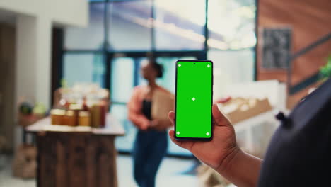 Retailer-holding-mobile-phone-with-greenscreen-layout