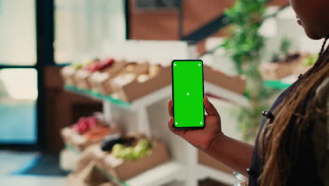 Merchant-holding-smartphone-with-greenscreen-display