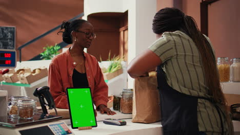 Woman-approaching-checkout-with-greenscreen-on-tablet