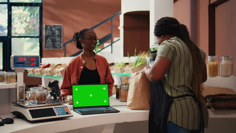 Vendor-using-a-laptop-with-greenscreen-layout-at-store-checkout