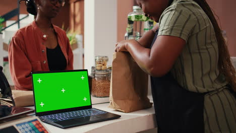 Merchant-selling-eco-goods-next-to-greenscreen-laptop