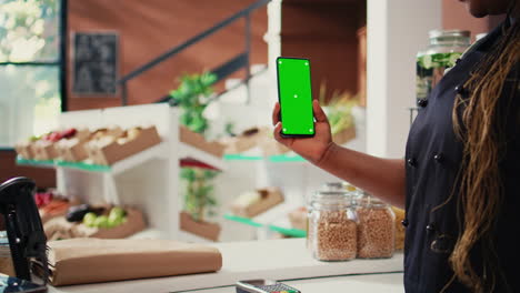 Store-vendor-holding-phone-with-greenscreen-display