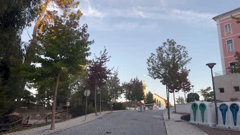 Tagesaufnahme-Der-Leeren-Straße-Der-Stadt-Mit-Niedrigem-Sonnenlichtwinkel,-Parkwanderbereich-Mit-Bäumen-Auf-Der-Einen-Seite-Und-Wohngebäude-Auf-Der-Anderen-Seite