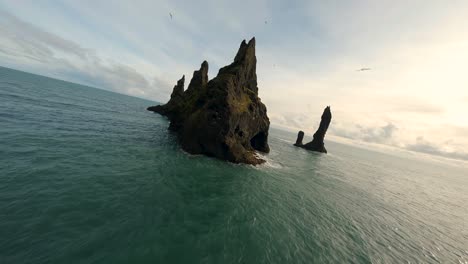 Flying-with-FPV-drone-over-the-Reynisdrangar-sea-stacks-in-the-Atlantic-Ocean-near-Vík,-Iceland