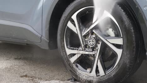 Rinsing-black-alloy-wheels-on-car