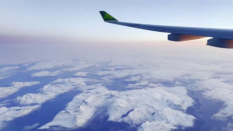 Flying-with-Aer-Lingus-plane-above-snowy-mountains-of-Greenland-at-dawn