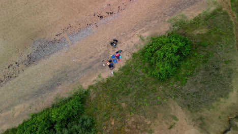 Descending-aerial-view-of-a-family-on-a-beach-in-Jurkalne,-Latvia
