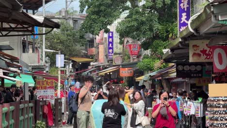 Los-Turistas-Piden-Deseos-Y-Encienden-Linternas-Hacia-El-Cielo-En-La-Antigua-Calle-De-Shifen,-Con-Vías-De-Ferrocarril-Que-Atraviesan-Tiendas-Y-Restaurantes-En-El-Distrito-De-Pingxi,-Taipei,-Taiwán.