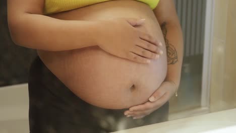 Mujer-Embarazada-De-Piel-Clara-Sosteniendo-Su-Vientre-De-Bebé-En-El-Espejo-Del-Baño.