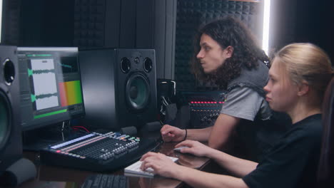 Female-audio-engineer-and-musician-create-song-in-music-recording-room.-Computer-screen-showing-DAW-software-interface-with-sound-track.-Modern-equipment-in-sound-recording-studio.-Music-production.