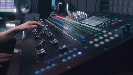 Audio-engineer-uses-mixing-console,-remote-control-for-adjusting-sound,-audio-mixer.-Musician-changes-the-volume-level,-creates-song-with-modern-equipment.-Sound-recording-studio.-Music-production.