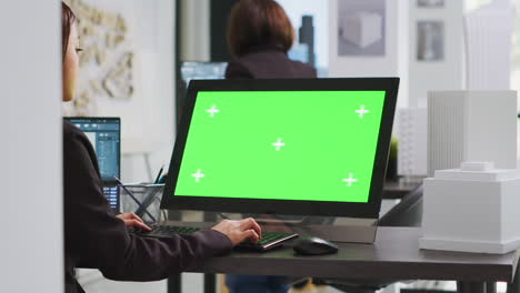 Cad-specialist-using-computer-with-greenscreen-at-office-desk