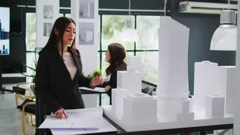 Architecture-office-employee-looking-at-building-model