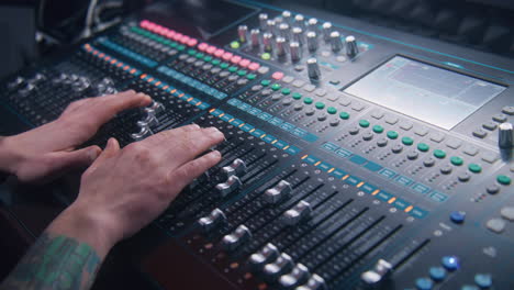 Close-up-hands-shot-of-sound-engineer-using-mixing-console,-remote-control-for-adjusting-sound,-audio-mixer.-Musician-creates-music,-makes-remix-for-DJ-set.-Sound-recording-studio.-Music-production.